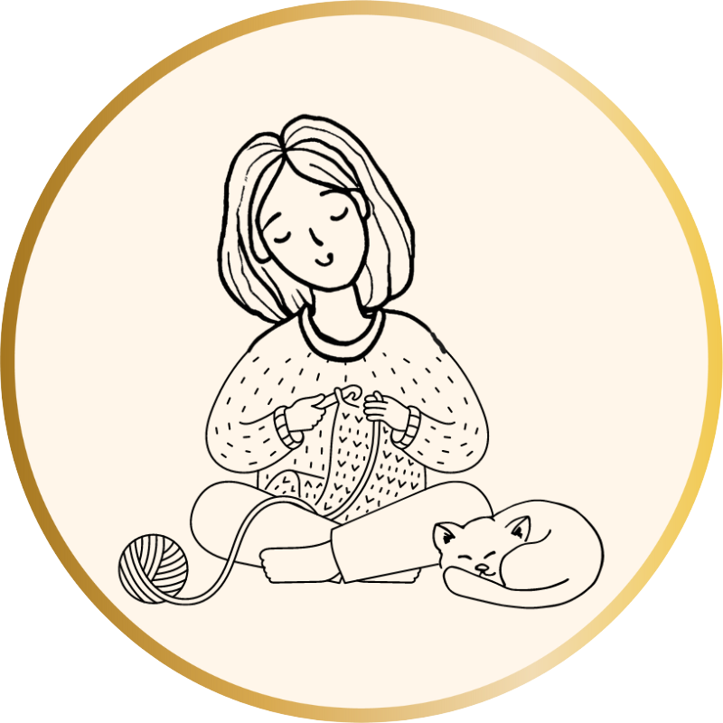 A woman sitting cross-legged crocheting with her cat at her side